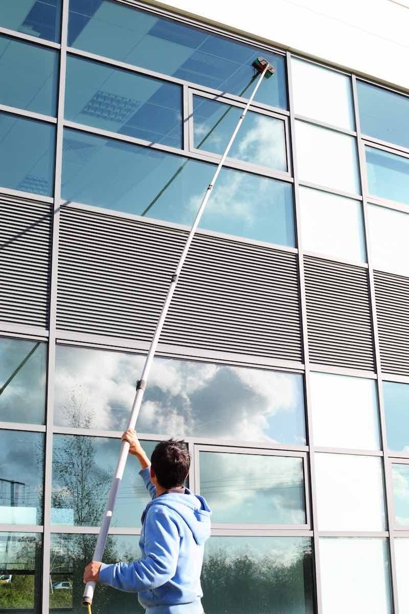 Water-fed pole cleaning the upper windows of a building from the ground